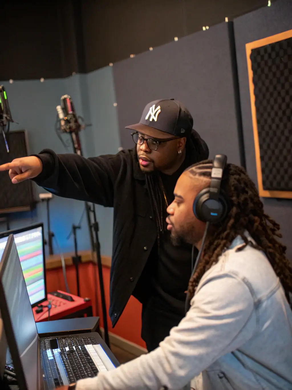 A behind-the-scenes image of a BRILLIANCE BOOK mentorship program, featuring an established musician guiding an emerging artist in a recording studio, surrounded by instruments and sound equipment.